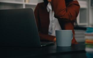 portrait d'une jeune femme asiatique pigiste à la main travaille son travail sur une tablette informatique dans un bureau moderne. faire un rapport d'analyse comptable sur les données d'investissement immobilier, le concept de systèmes financiers et fiscaux. photo