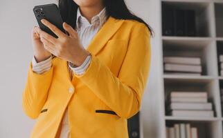 jeune femme d'affaires souriante utilisant un smartphone près d'un ordinateur au bureau, espace de copie photo