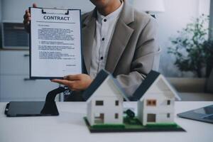 L'agent immobilier a parlé des termes du contrat d'achat de maison et a demandé au client de signer les documents pour conclure le contrat légalement, les ventes de maisons et le concept d'assurance habitation. photo