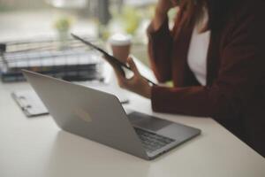 coup de une asiatique Jeune affaires femelle travail sur portable dans sa poste de travail. photo