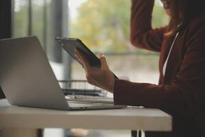 coup de une asiatique Jeune affaires femelle travail sur portable dans sa poste de travail. photo