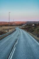 incurvé asphalte Autoroute avec électricité pylône parmi le volcanique champ pendant l'automne dans Islande photo