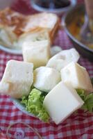 nourriture assiette de fromage cubes et salade sur à carreaux nappe de table photo