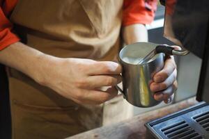 en train de préparer Frais café, en portant lanceur pour fumant lait. préparation et un service concept photo