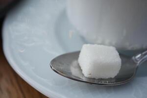 tasse de thé et une sucre cube sur table photo