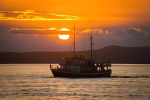 ai généré bateau glisse en dessous de couchers de soleil d'or lueur sur Lac Baïkal photo