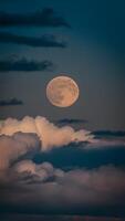 ai généré Capturer plein lune jette un éthéré lueur au milieu de dérive des nuages verticale mobile fond d'écran photo