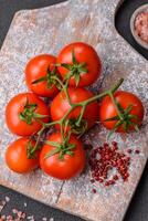 Frais rouge Cerise tomates sur une branche sur une foncé béton Contexte photo