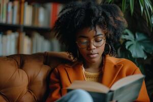 ai généré une élégant africain américain femme avec des lunettes est assis sur le canapé et lit une livre. littéraire loisir photo