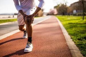 Jeune Afro-américain homme est blessé tandis que jogging. il a douleur dans genou. photo