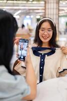 une femme prise une image de sa ami avec une Nouveau vêtir, ayant une amusement achats journée ensemble. photo