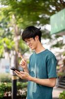 une homme est montrant le sien indice doigt, eu un idée, en utilisant le sien téléphone intelligent tandis que permanent dans le ville. photo