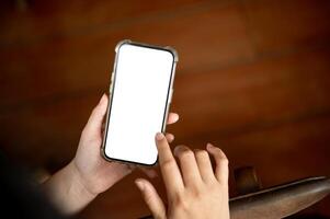 une fermer image de une femme en utilisant sa téléphone intelligent à l'intérieur. une Écran blanc téléphone intelligent maquette photo
