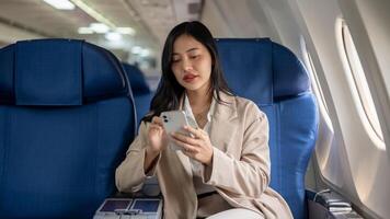 un attrayant asiatique femme d'affaires tour sur le avion mode sur sa téléphone intelligent avant décoller. photo