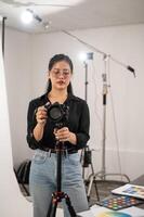 une professionnel asiatique femelle photographe est ajustement sa dslr caméra sur une trépied rester. photo