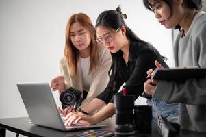 une professionnel asiatique femelle photographe est travail avec sa assistants dans une séance photo studio.