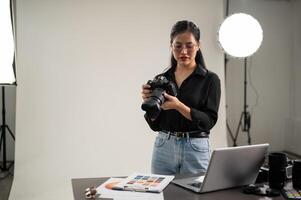 une professionnel, attrayant asiatique femelle photographe est ajustement sa dslr caméra pour une séance photo. photo
