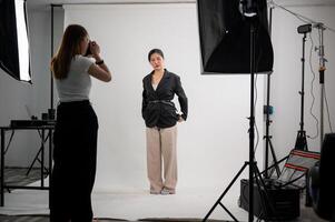 un attrayant asiatique femelle modèle est posant pour une photographe dans une moderne mode studio. photo