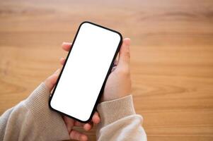 une fermer coup de une femme en utilisant sa téléphone intelligent à une table à l'intérieur. photo