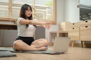 une content, en forme Jeune asiatique femme est Suivant un en ligne faire des exercices à maison. photo