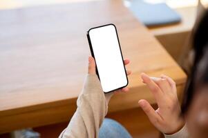 une fermer coup de une femme en utilisant sa téléphone intelligent à une table à l'intérieur. photo