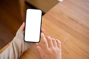 une fermer coup de une femme en utilisant sa téléphone intelligent à une table à l'intérieur. photo