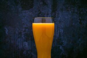 verre avec mangue jus. bleu Contexte. photo