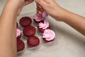 femme mains décorer petits gâteaux avec crème fromage Glaçage. photo