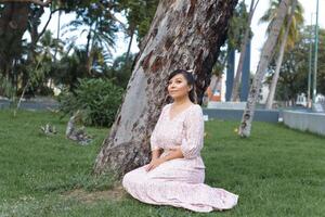 femme avec positif attitude assise dans le herbe dans une Publique jardin. photo