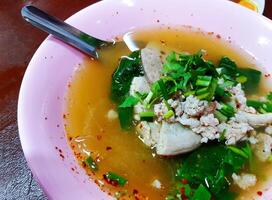 proche en haut bouilli porc du sang avec haché, entrailles et légume dans rose bol sur tableau. asiatique et chaud aliments. photo