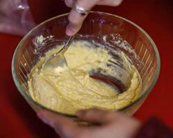 une bol de végétarien pain au maïs Battre étant mixte en haut à être à la cuillère dans petit gâteau papiers photo