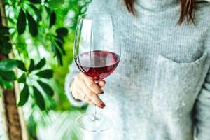 femme en portant une verre de rouge du vin à une dîner fête photo