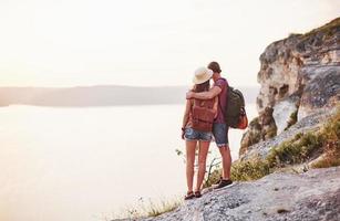 loin. un jeune couple a décidé de passer ses vacances de manière active au bord du magnifique rocher avec un lac en arrière-plan