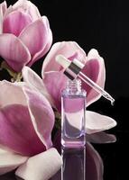 une bouteille de parfum avec une rose fleur dans le noir Contexte photo