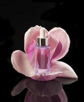 une bouteille de parfum avec une rose fleur dans le noir Contexte photo