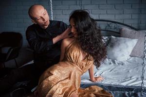 toucher doux. un couple en tenue classique est assis devant le magnifique lit décoré de luxe