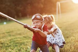 tout est question de travail d'équipe. c'est un tir à la corde avec papa sur une belle herbe d'une journée chaude et ensoleillée photo