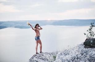 humeur du coucher du soleil. jolie fille touristique posant au bord de la montagne avec un lac d'eau claire en arrière-plan photo