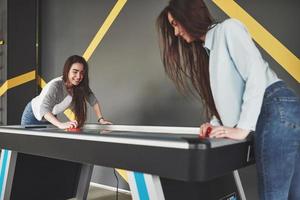 deux belles jumelles jouent au hockey sur air dans la salle de jeux et s'amusent photo