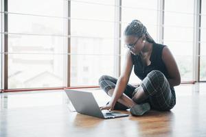 une jeune femme afro-américaine est heureuse avec un ordinateur portable.