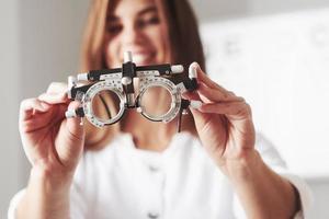 photo focalisée. femme médecin montrant le petit phoropter en le tenant à deux mains