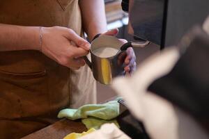 le café machine est faire mousser lait. barista mains tenir une cruche de lait. photo