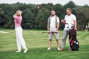 trois amis passent du bon temps sur le terrain à jouer au golf et à regarder le tir photo