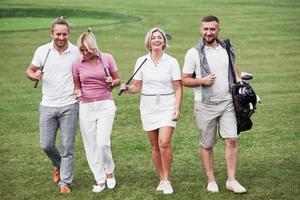 amis joyeux passant du temps sur le terrain de golf avec des bâtons et de la bonne humeur photo