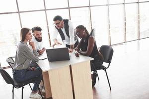 l'équipe est à l'écoute de son manager. groupe d'indépendants travaillant dans le bureau spacieux avec de grandes fenêtres photo