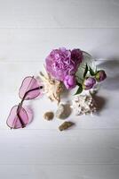 rose lunettes, pivoines et mer coquilles sur une blanc en bois tableau. romantique été plat poser. photo