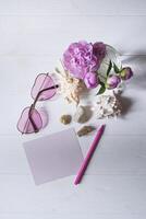 rose lunettes, pivoines et mer coquilles sur une blanc en bois tableau. romantique été plat poser. photo