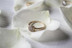 d'or bague sur blanc pétales de des roses. photo