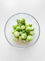 bol de brut Bruxelles choux sur blanc surface. Frais vert légumes, en bonne santé alimentaire, végétarien nourriture concept avec copie espace. photo