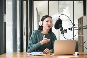 une femme est séance à une bureau avec une portable et une microphone photo